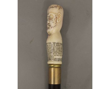 A walking stick with a carved bone phrenology head handle. 90.5 cm long.