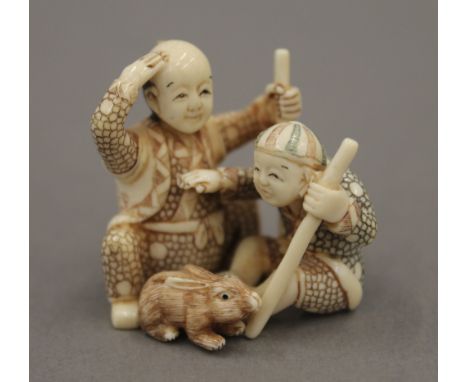 A late 19th/early 20th century Japanese carved ivory netsuke of two boys playing with a rabbit. 3.5 cm high.