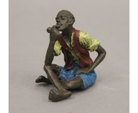 A cold painted bronze model of a boy smoking a pipe. 6 cm high.