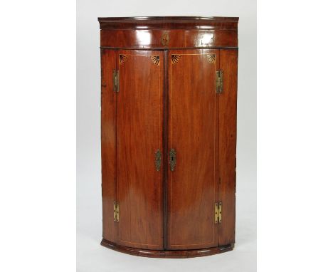 GEORGE III INLAID MAHOGANY BOW FRONTED CORNER CUPBOARD, the moulded cornice above a frieze with central oval inlay of a pedes