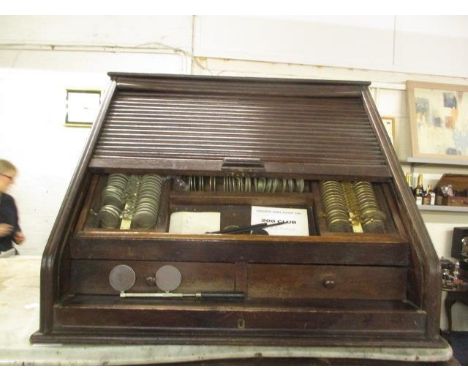 An early 20th century optician's oak cabinet with a tambour front, enclosing a removable tray with lenses over two drawers an