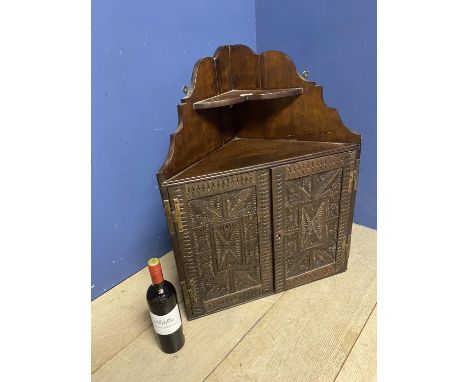 AN oak hanging wall cabinet, with carved wooden doors below a corner shelf, some minor wear, 30cm H x 60cm W approx 