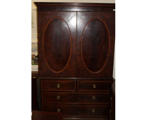A Regency mahogany and satinwood banded linen press, the moulded cornice above two oval panelled doors enclosing four linen s