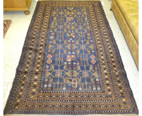 A Beluch rug, the central panel with repeating pattern in hickory and chestnut brown, with all-over flower head design in lim