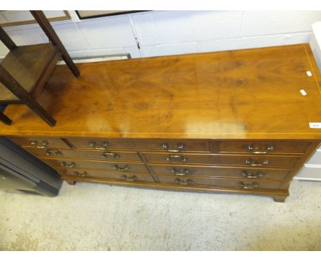 A modern reproduction yew wood veneered multi-drawer chest upon bracket feet