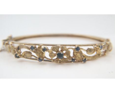 9ct gold ladies bangle designed with flowers and leaves set with blue sapphires, 15g. UK P&amp;P Group 0 (£6+VAT for the firs