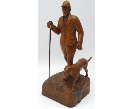 K. Bateson craftsman carved oak model of a Huntsman with thumbstick, walking with a Hound, on oval naturalistic base, signed 