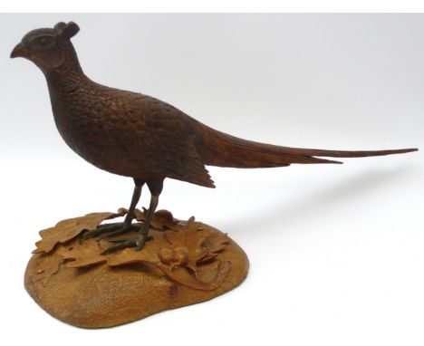 K. Bateson craftsman carved oak model of a standing Cock Pheasant, with gilt metal legs on oval base carved with Acorns &amp;