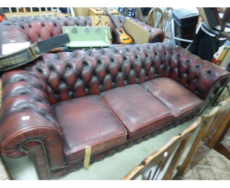 A three seater red leather button back Chesterfield settee