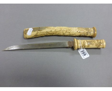 A small Japanese bone handled knife; complete with bone scabbard; carved with scenes of people