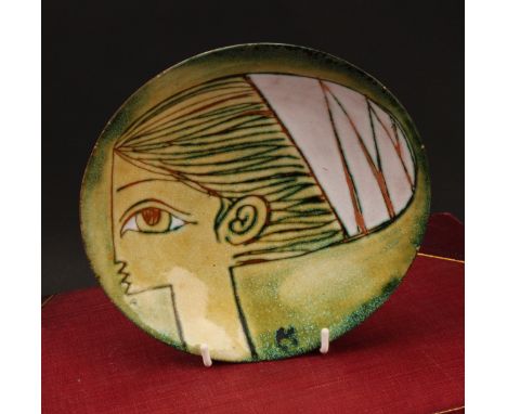 A contemporary studio pottery circular pedestal dish, sgraffito decorated with a stylised portrait of a female wearing a head