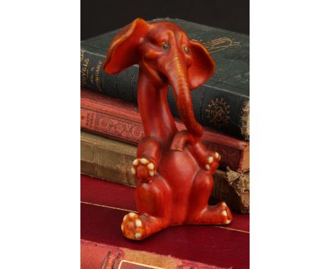 An Art Deco Grafton China comical model of an elephant, seated with elongated neck and curling trunk, glazed in orange, pair 