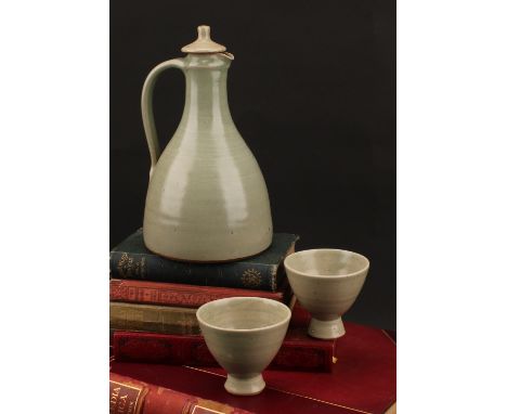 A Leach Pottery sake carafe and stopper with pair of conical sake glasses, glazed in celadon green, the carafe 21cm high, imp