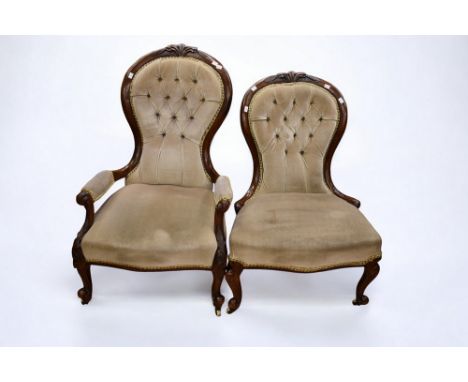 A pair of Victorian mahogany button back with green velvet sofa chairs with carved features and padded arms, standing on porc