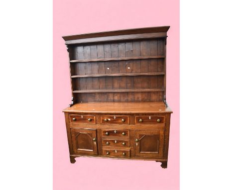 An early 19th Century solid oak kitchen dresser with three shelf plate rack above a block base with three central drawers, tw