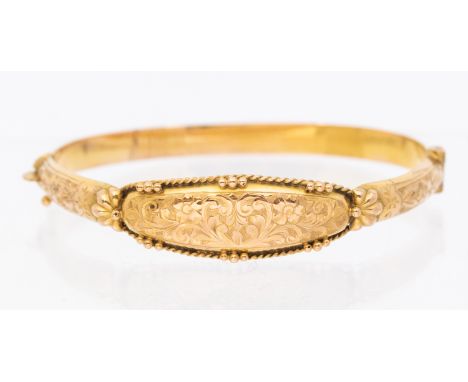 An early 20th century 9ct gold hinged bangle dated 1918, comprising scroll and foliate decoration, the front heart shaped eng