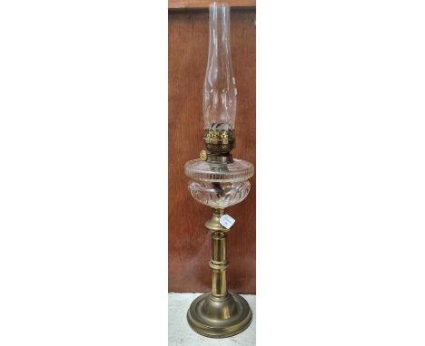 Early 20th Century double oil burner lamp, having clear glass chimney above a clear glass reservoir standing on a brass base.