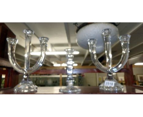 A pair of glass candelabra and a glass candlestick.