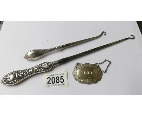 A large silver handled button hook, a smaller example and a silver wine label.