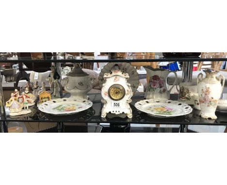 A shelf of continental porcelain including figures, ribbon plates and a clock