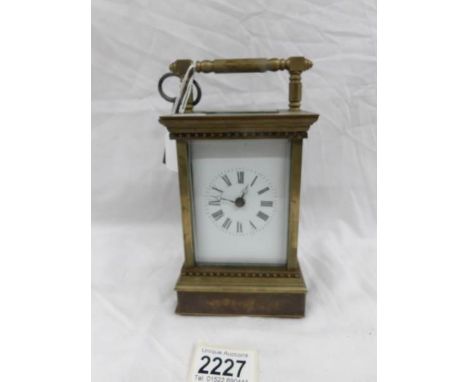 A brass carriage clock with decorated side panels.