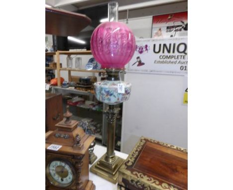 A Victorian Corinthian column oil lamp with hand painted glass font and cranberry glass shade.