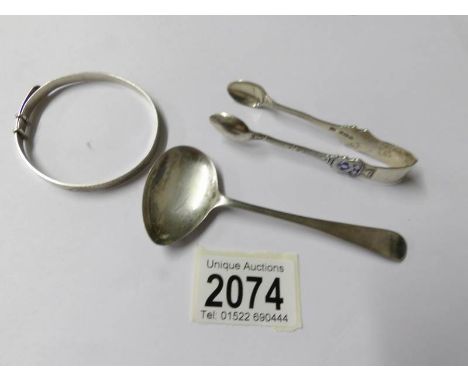 A silver sauce ladle, silver sugar nips and silver bangle.