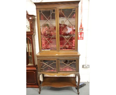 An Edwardian mahogany display cabinet, the glazed base with under shelf supports a red velvet lined two door astragal glazed 