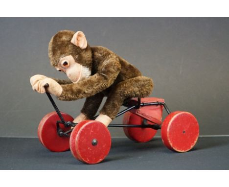 Steiff Record Peter Monkey 1921, lacking button to ear, seated on a wooden red painted and metal pull along cart, 26cm high 