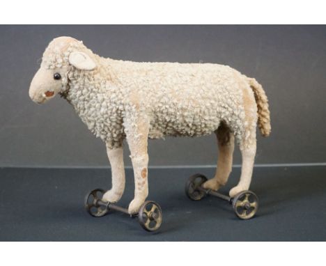 Early 20th century Push-along Sheep, straw-filled and mounted on iron wheels, possibly Steiff, 25cm long 