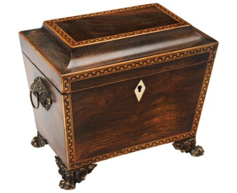 A REGENCY ROSEWOOD SARCOPHAGUS TEA CADDY with inlaid borders, brass side handles and fancy claw feet, the interior with two l
