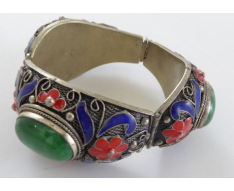 A Chinese silver bracelet with green centralised stones, blue and red enamel, bearing Chinese character marks.