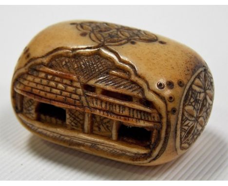 Meiji period ivory netsuke, of oblong form, carved and pierced with opposing building, the ends with cross-hatched engraving,