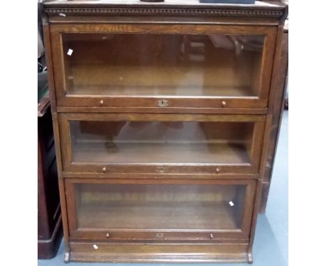 'The Lebus Bookcase' oak three section bookcase with shaped gallery upon plinth base, width 34.75in