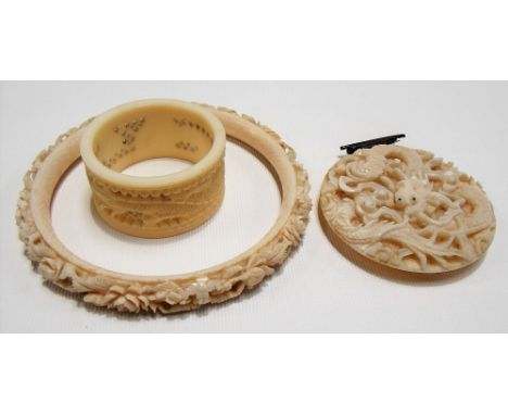 Early 20th Century Chinese export ivory foliate carved bangle, napkin ring and circular dragon carved brooch (3)