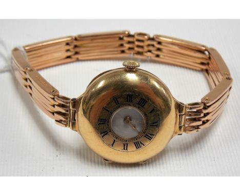 18ct gold early 20th Century ladies half hunter wristwatch with white enamel dial with Roman Numerals, upon a 15ct rose gold 
