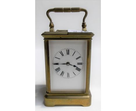 Small brass carriage timepiece with white enamel dial with Roman numerals, the movement striking on a gong, height overall 5i