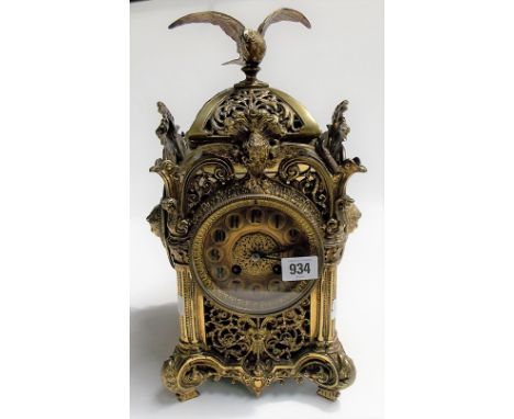 French ornate brass two train mantel clock, the case overall foliate scroll cast and pierced and surmounted with a bird, the 
