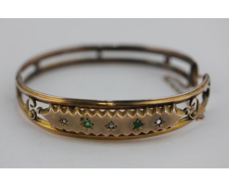 A 9ct gold bangle set with emeralds and small diamonds (a/f one stone missing), 8.7g