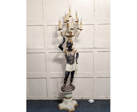 A Venetian style Blackamoor figural standard lamp with standing figure holding a ten light candelabra, on shaped base with gi