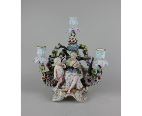 A Sitzendorf porcelain three light figural candelabrum of a seated woman and Cupid against floral encrusted branches topped w