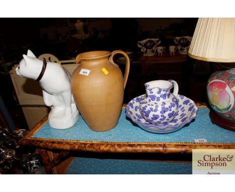 A stone glazed pitcher; a white glazed china cat ornament; and a continental blue and white pottery jug and bowl 