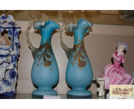 A pair of pale blue glass and enamel decorated ewers with frilled decoration