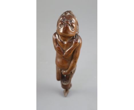 A Japanese cherrywood okimono netsuke of a farmer, early 19th century, the figure with gurning expression and black stone ins