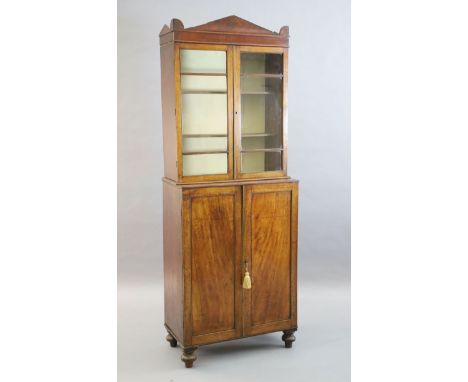 A Regency mahogany collector's cabinet, with architectural cornice and two glazed doors over two panelled doors enclosing an 