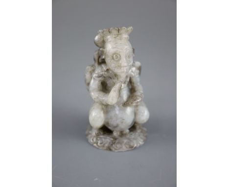 A Chinese grey jade figure, the stylised figure with wings and ribbon tied hair, in a crouching position, the stone with dark