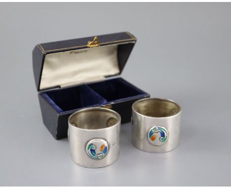 A cased pair of Edwardian Art Nouveau silver and enamel napkin rings, by William Hair Haseler, Birmingham, 1904, 38mm, gross 