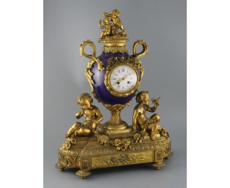Vernet, Rue du Bac 42. A 19th century French ormolu and bleu du roi porcelain mantel clock, of urn form, flanked by putti hol