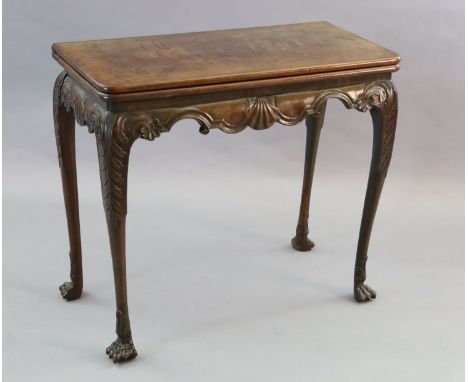 A mid-18th century Irish carved walnut folding top card table, with scallop and scroll carved apron and acanthus carved legs 