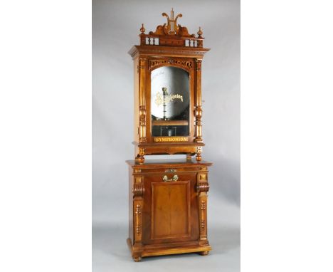 A late 19th century German walnut cased upright Symphonion, with lyre shaped pediment, pilaster flanked glazed door enclosing